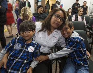 Isabel Medina, de 41 años, se abraza a sus hijos, Rayan (izqda), de seis años, y Jimmy Ortiz (dcha), de ocho, durante el anuncio del presidente de EEUU, Barack Obama, de la nueva reforma migratoria, el 20 de noviembre de 2014 (AFP | Ringo Chiu)